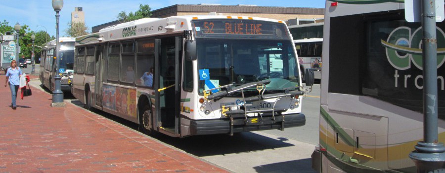A Codiac Transpo city bus sits at the curb awaiting passengers, while running on the Route 52 "Blue Line"