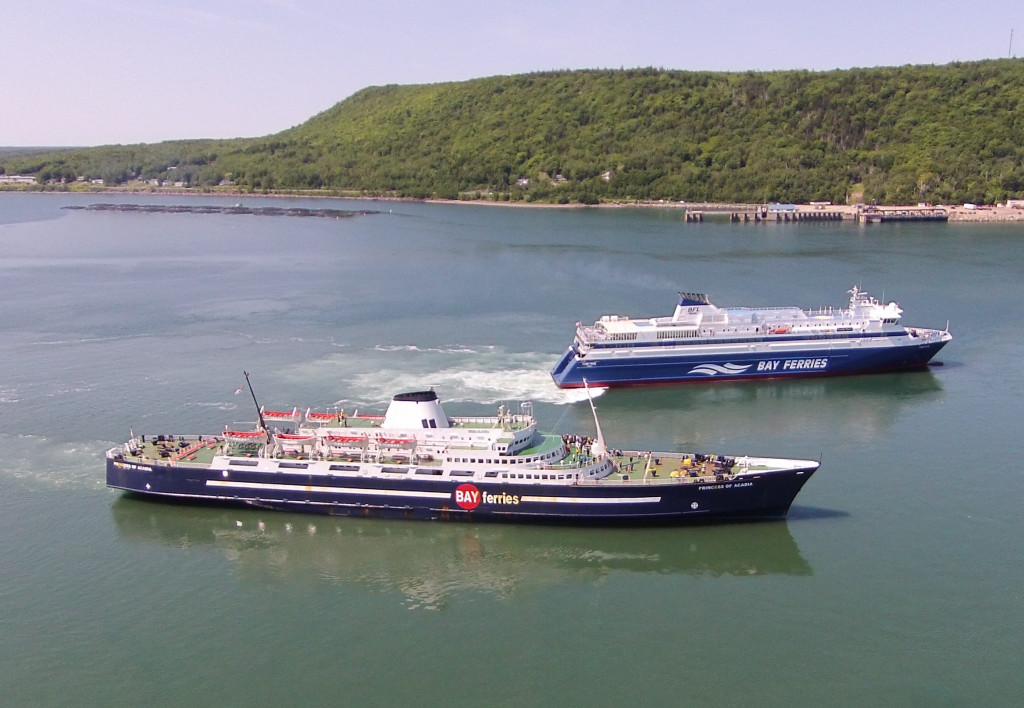 Two large ferry boats, one visibly newer than the other, sailing in the Bay of Fundy