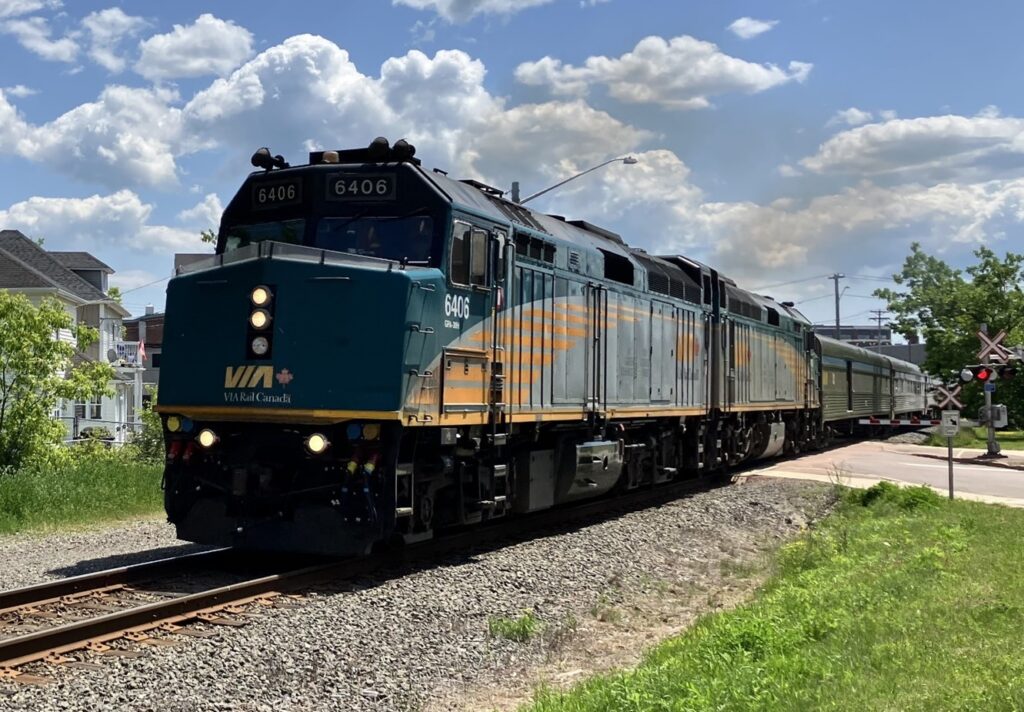 A VIA Rail train crosses over a roadway as it passes through Moncton NB on a sunny day.